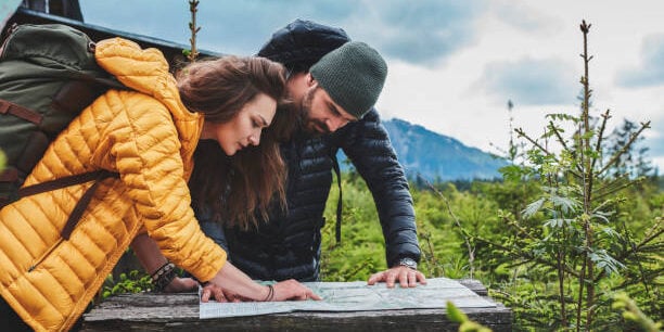 Young couple in the woods planning trip. Using map
